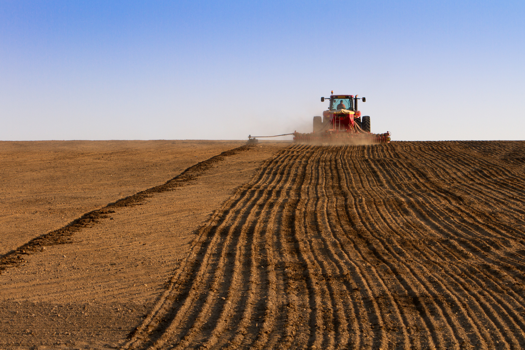 Dirt field with a tractor plowing it