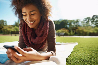 Young girl on a blanket outside looking at smart phone